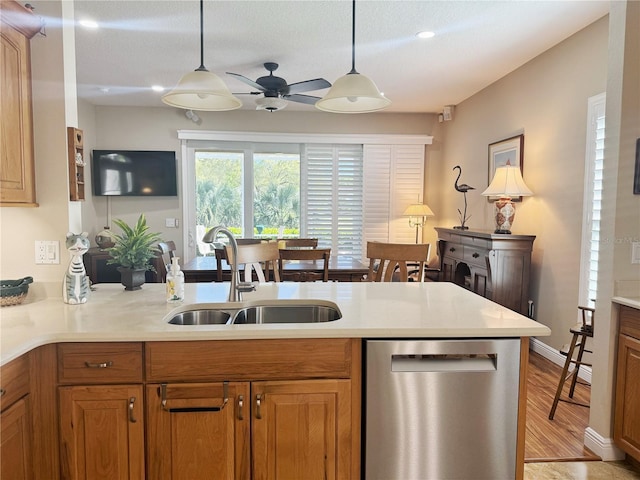 kitchen featuring hanging light fixtures, stainless steel dishwasher, a sink, and brown cabinets