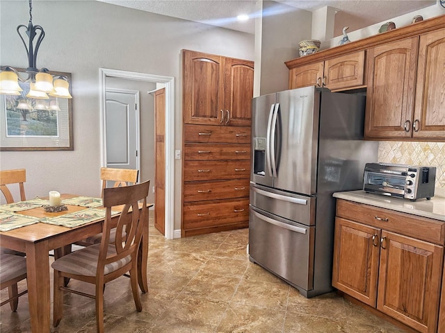 kitchen with brown cabinetry, decorative backsplash, light countertops, and stainless steel fridge with ice dispenser