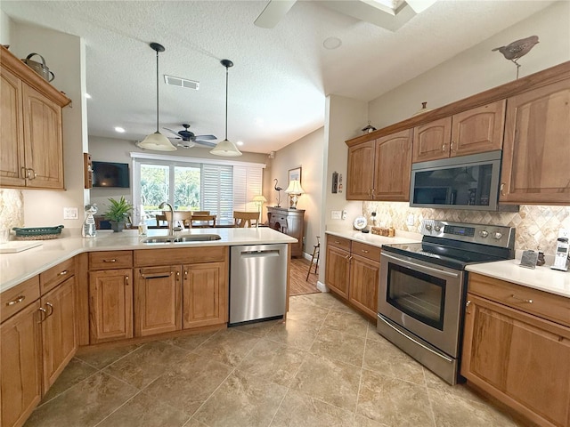 kitchen with visible vents, appliances with stainless steel finishes, a sink, ceiling fan, and a peninsula