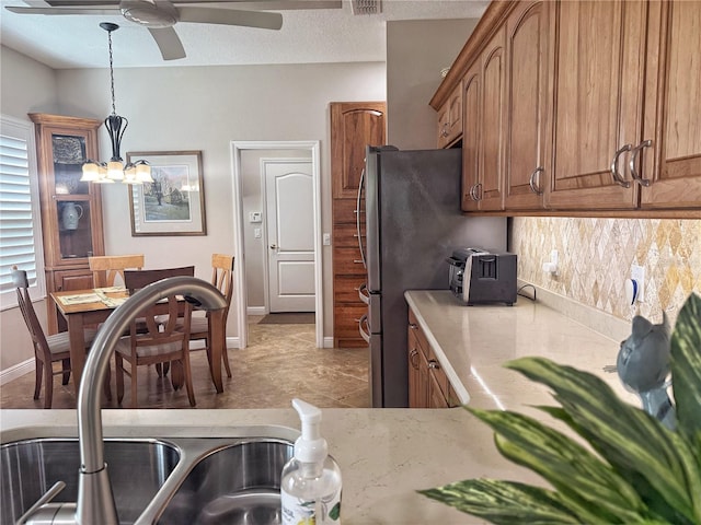 kitchen with brown cabinets, decorative light fixtures, a textured ceiling, a sink, and ceiling fan with notable chandelier