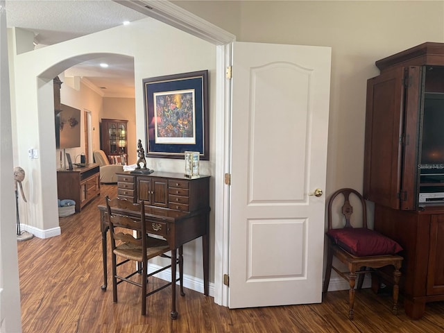 hall with arched walkways, dark wood-type flooring, and baseboards