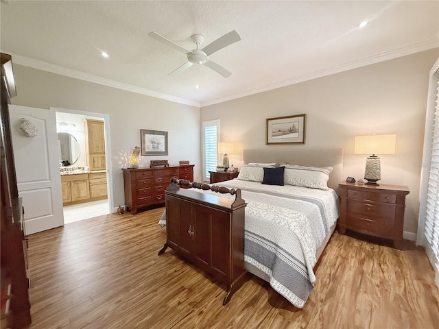 bedroom featuring light wood finished floors, baseboards, ensuite bath, ceiling fan, and crown molding