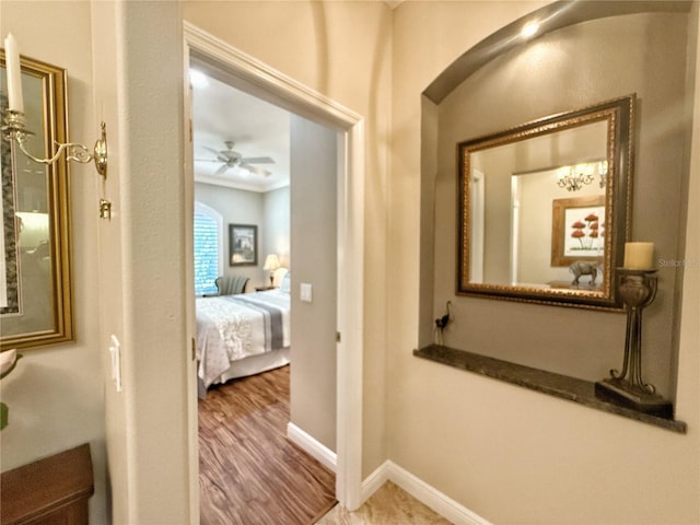 hall with ornamental molding, arched walkways, baseboards, and wood finished floors