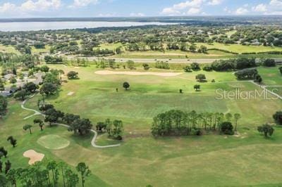 drone / aerial view with a water view and golf course view