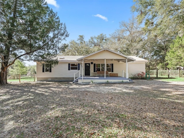 rear view of property featuring fence, metal roof, and a ceiling fan