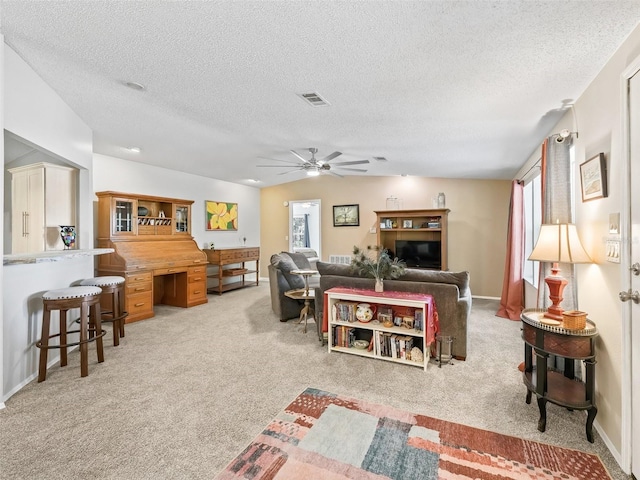 living area featuring lofted ceiling, visible vents, a ceiling fan, carpet flooring, and a textured ceiling