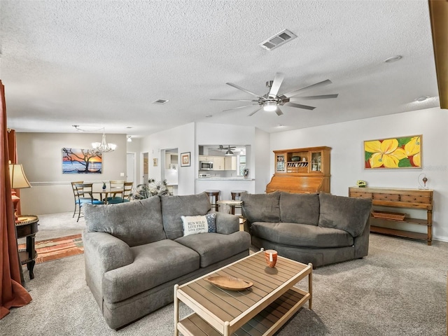 living room featuring ceiling fan with notable chandelier, a textured ceiling, carpet flooring, and visible vents