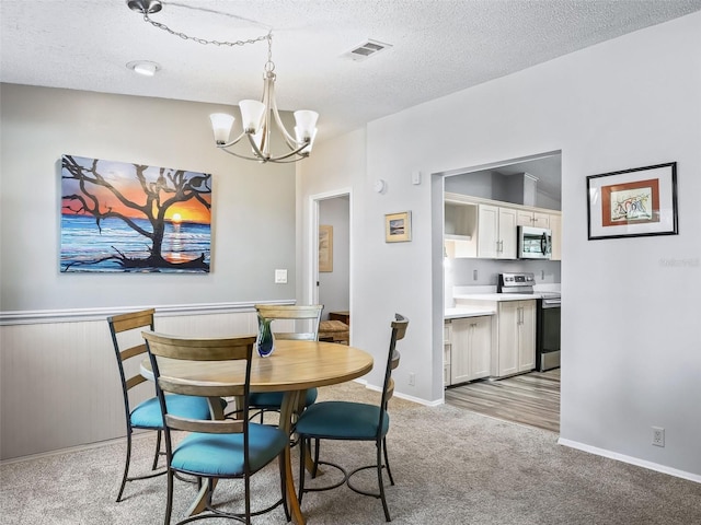 dining room with light carpet, baseboards, visible vents, a textured ceiling, and a notable chandelier