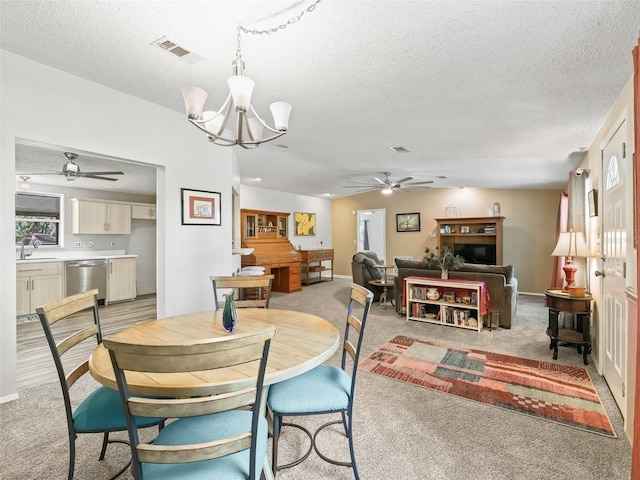 dining area featuring light carpet, visible vents, a textured ceiling, and ceiling fan with notable chandelier