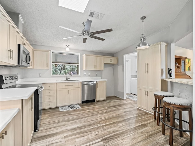 kitchen with visible vents, appliances with stainless steel finishes, light countertops, light wood-type flooring, and a sink