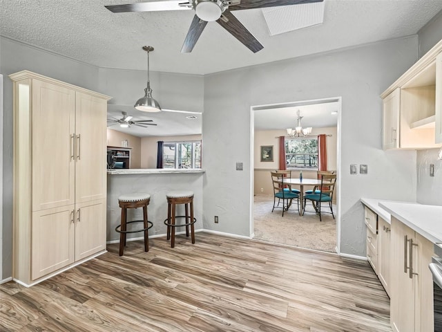 kitchen featuring ceiling fan with notable chandelier, a textured ceiling, wood finished floors, and pendant lighting