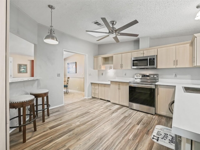 kitchen with light wood finished floors, open shelves, light countertops, hanging light fixtures, and appliances with stainless steel finishes