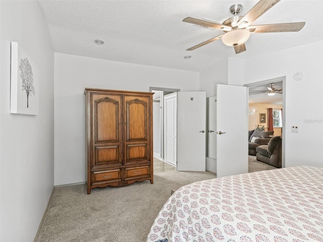 bedroom featuring light carpet, a textured ceiling, and a ceiling fan