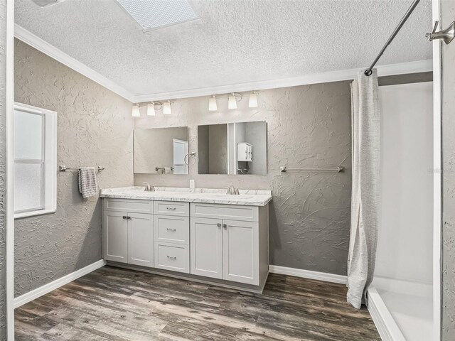 bathroom with a sink, wood finished floors, and a textured wall