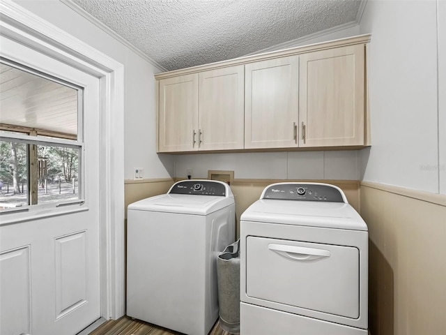 clothes washing area featuring washing machine and dryer, cabinet space, and a textured ceiling