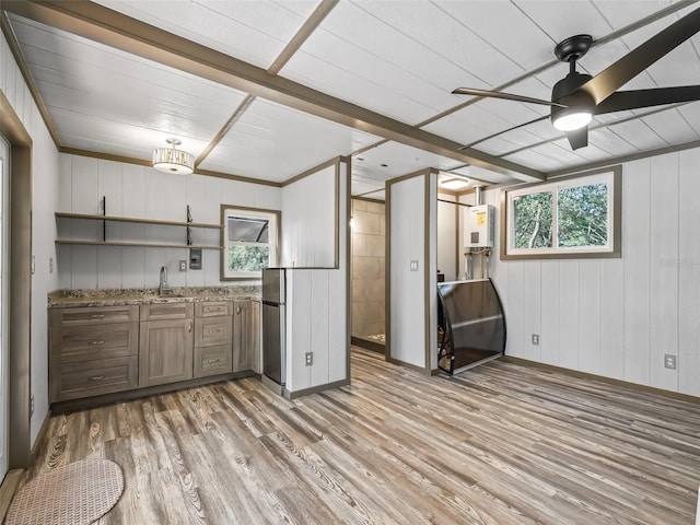 kitchen featuring light stone counters, a sink, a ceiling fan, freestanding refrigerator, and light wood finished floors