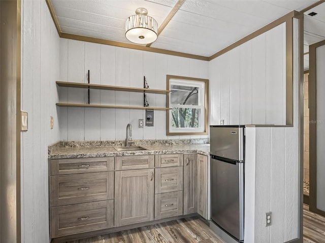 kitchen featuring wood finished floors, freestanding refrigerator, light stone countertops, open shelves, and a sink