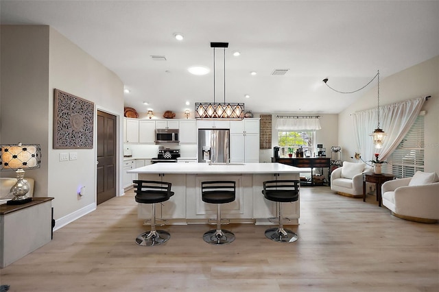 kitchen with vaulted ceiling, white cabinets, visible vents, and stainless steel appliances