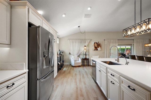 kitchen with light countertops, vaulted ceiling, light wood-style flooring, stainless steel appliances, and a sink