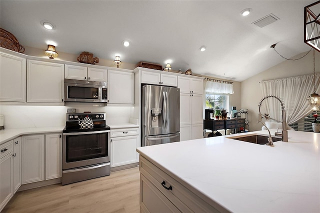 kitchen featuring visible vents, light wood-style flooring, a sink, appliances with stainless steel finishes, and white cabinetry