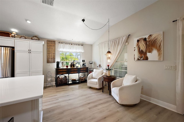 living area featuring visible vents, baseboards, light wood-style floors, and lofted ceiling