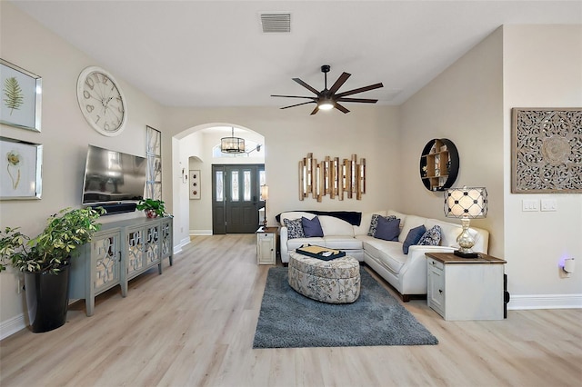 living area featuring baseboards, light wood-type flooring, arched walkways, and visible vents