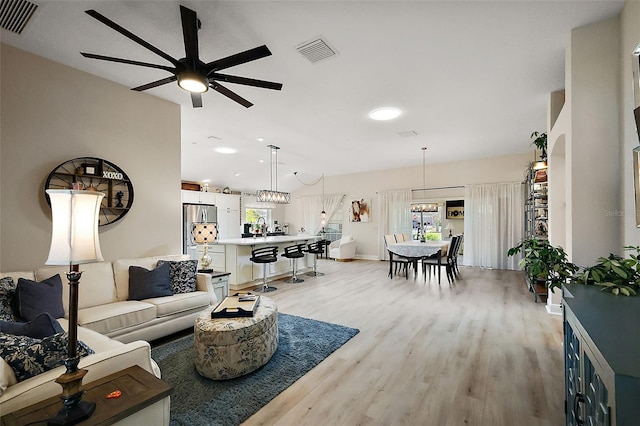 living room with visible vents, ceiling fan, baseboards, and light wood-style floors