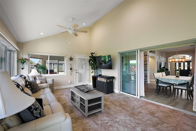 living room featuring ceiling fan with notable chandelier, high vaulted ceiling, and baseboards