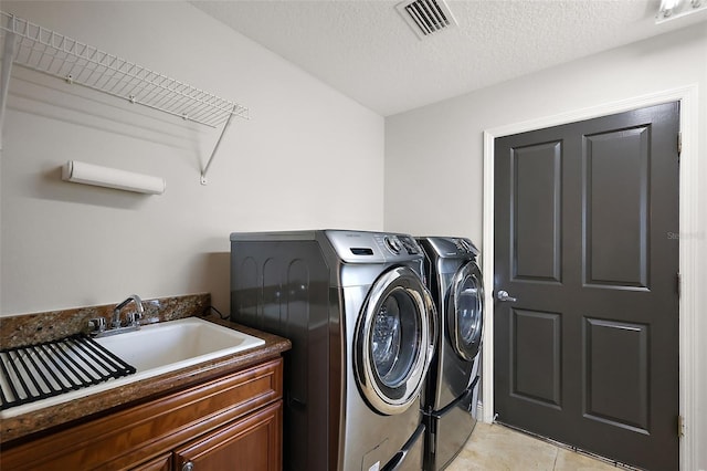 clothes washing area with washer and dryer, visible vents, cabinet space, and a sink