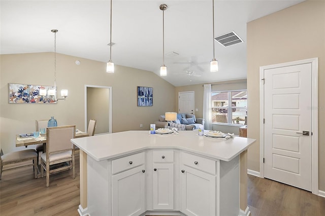 kitchen with light countertops, visible vents, light wood-style flooring, white cabinets, and vaulted ceiling