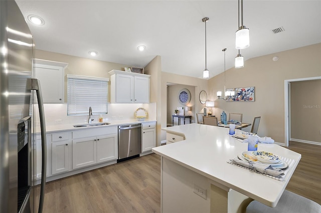 kitchen featuring lofted ceiling, stainless steel appliances, a sink, light countertops, and a center island