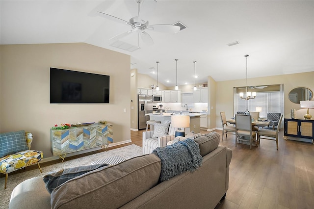 living room with visible vents, vaulted ceiling, and wood finished floors