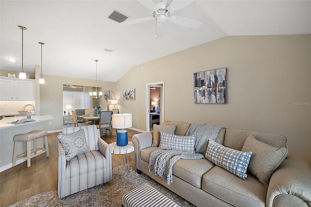 living area with baseboards, visible vents, dark wood-type flooring, vaulted ceiling, and ceiling fan with notable chandelier