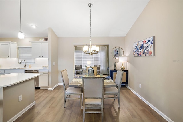 dining space with lofted ceiling, light wood-style flooring, baseboards, and an inviting chandelier