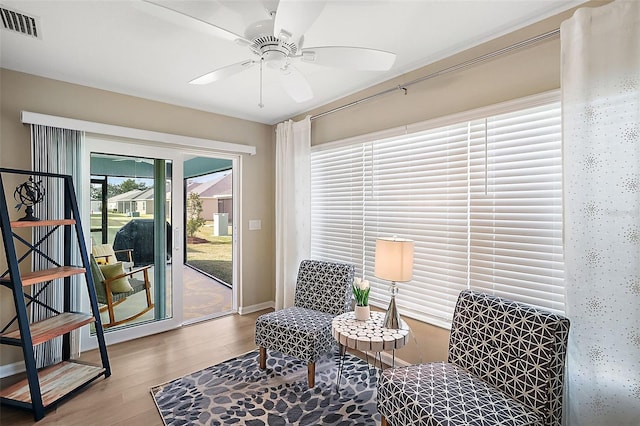 living area with visible vents, ceiling fan, and wood finished floors