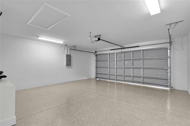 garage featuring a garage door opener, concrete block wall, and electric panel