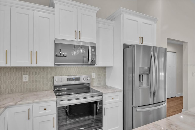 13334 SW 107th St, Dunnellon, FL 34432 - kitchen with appliances with stainless steel finishes, white cabinets, tasteful backsplash, light stone counters, and wood finished floors