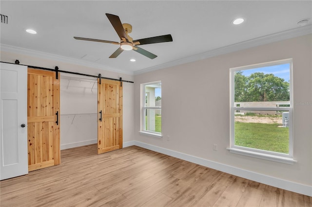 13334 SW 107th St, Dunnellon, FL 34432 - unfurnished bedroom featuring a barn door, crown molding, multiple windows, light wood-type flooring, and a spacious closet
