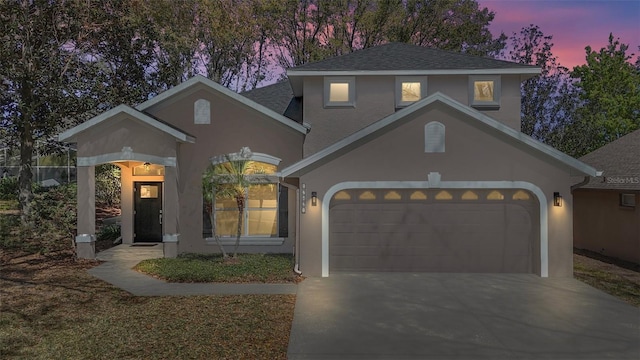 view of front of house featuring driveway, an attached garage, roof with shingles, and stucco siding