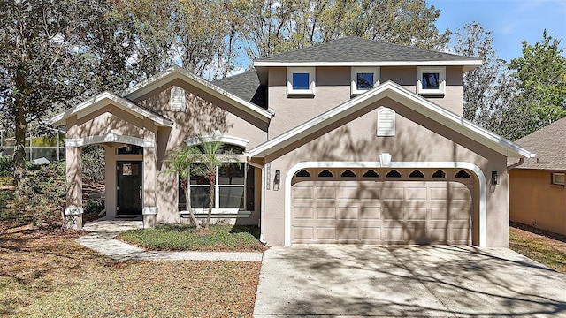 traditional-style house with a garage, concrete driveway, roof with shingles, and stucco siding