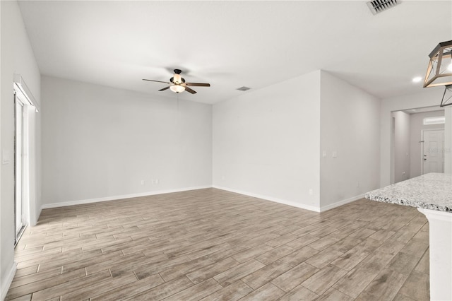 unfurnished living room featuring light wood finished floors, visible vents, baseboards, and ceiling fan