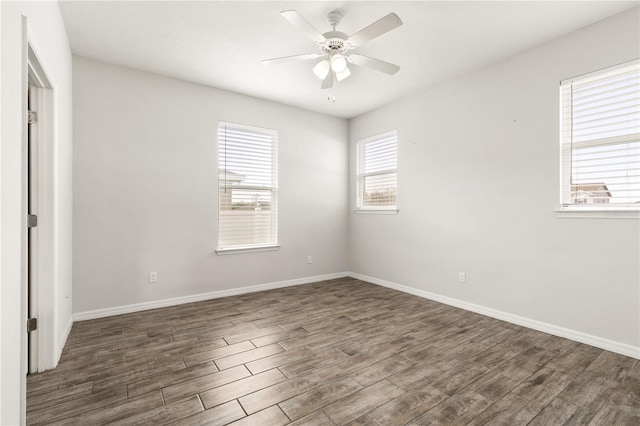 spare room featuring baseboards, wood finished floors, and a ceiling fan