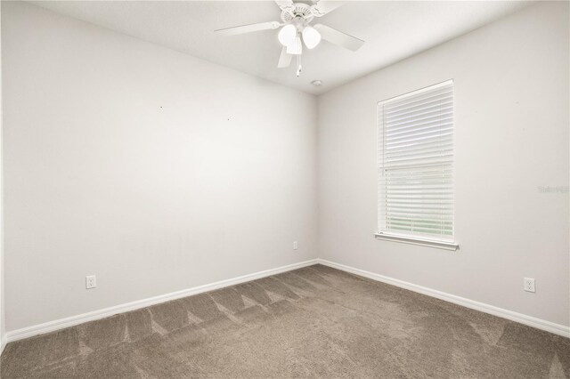 carpeted spare room featuring a ceiling fan and baseboards