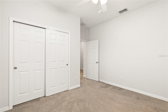 unfurnished bedroom with visible vents, a closet, baseboards, light colored carpet, and ceiling fan