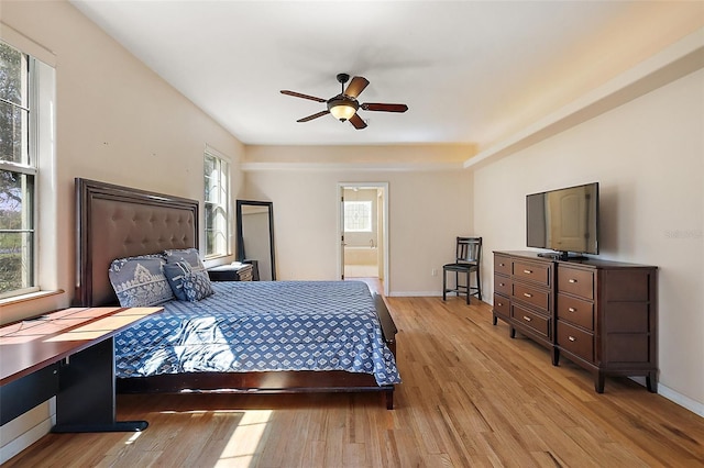 bedroom featuring light wood-style floors, ensuite bath, baseboards, and a ceiling fan