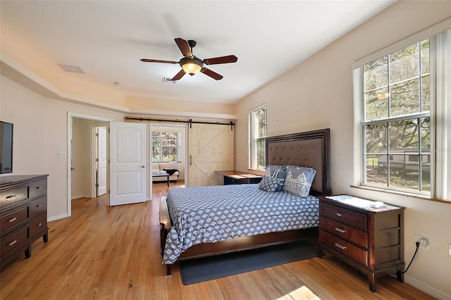 bedroom with light wood-style flooring, baseboards, and a barn door