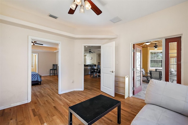 living room with light wood-type flooring, visible vents, and baseboards