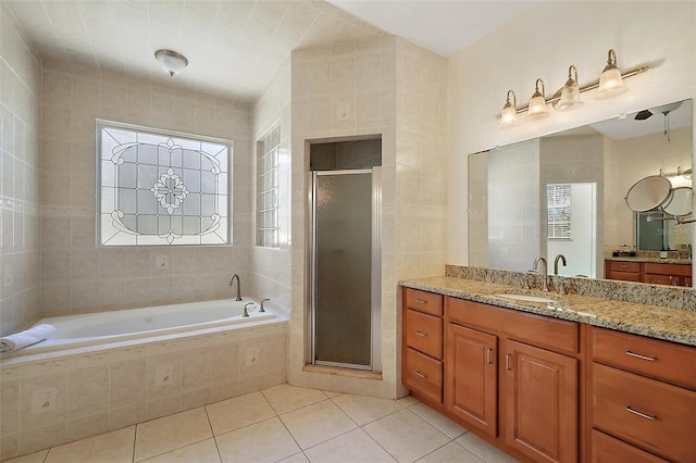 bathroom featuring a stall shower, tile patterned flooring, a garden tub, and vanity