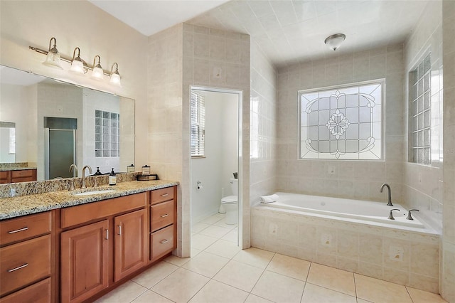 full bathroom featuring tile patterned flooring, a healthy amount of sunlight, a garden tub, and vanity