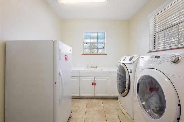 clothes washing area with washing machine and dryer, light tile patterned flooring, a sink, and cabinet space